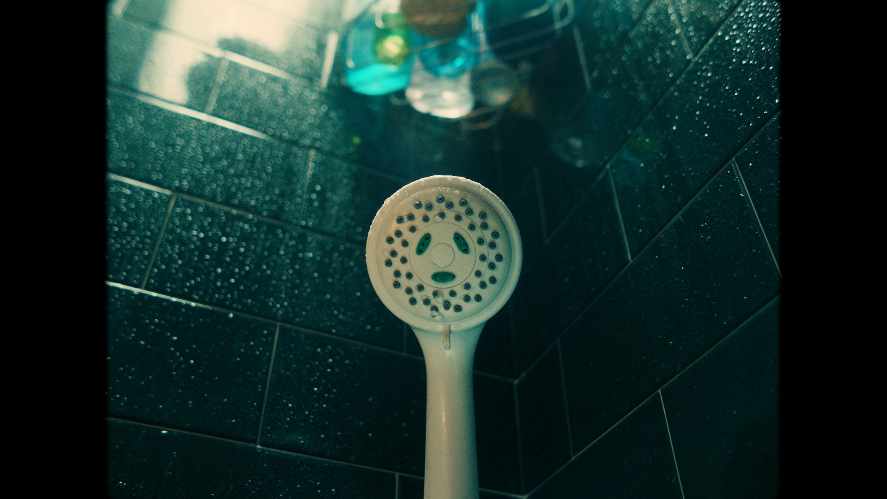 White showerhead in black tiled bathroom