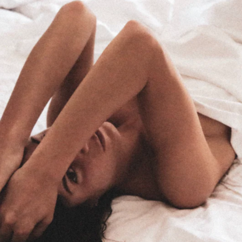 Women laying in bed covered in white sheet